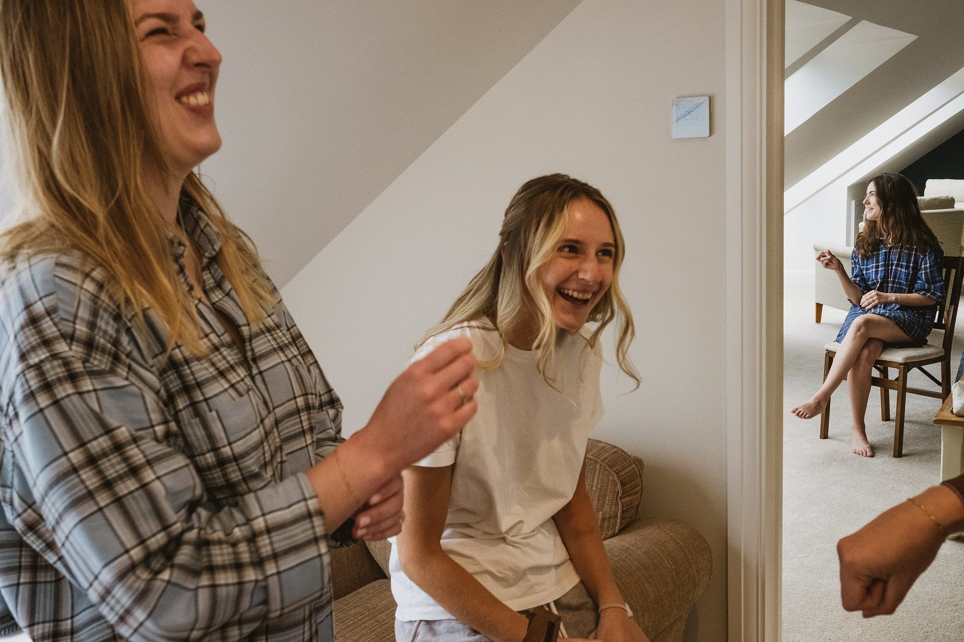 Bridesmaids laughing with bride in background having her hair and make up done in Surrey