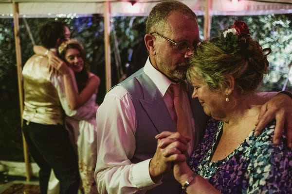 layered documentary style wedding photograph. Two couples slow dance together - a bride and groom in the background and the mother and father of the bride in the foreground, showing the symmetry between the relationships