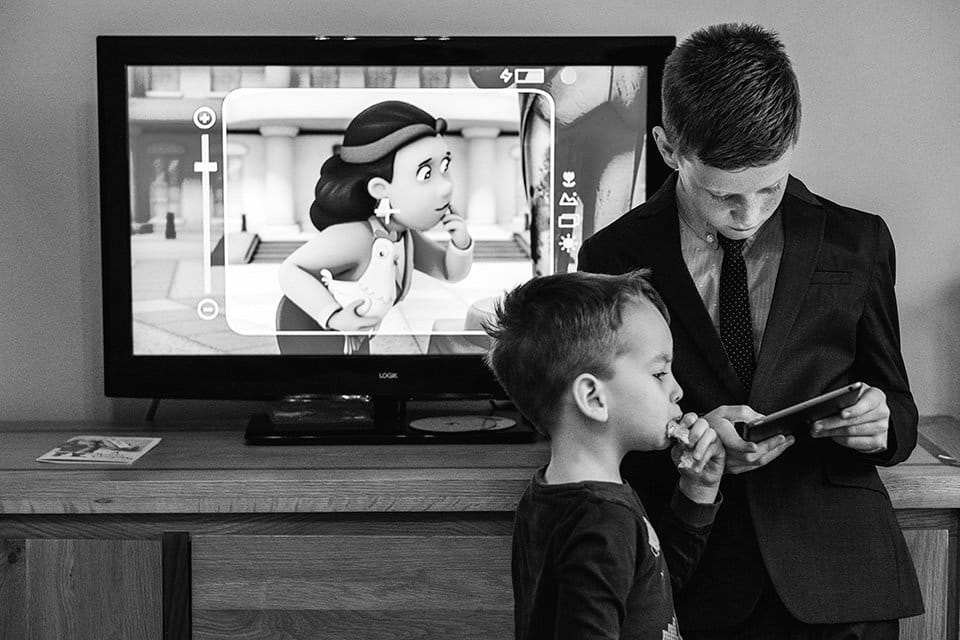 Street-style documentary wedding photograph - character on TV is given the appearance of interacting with two boys in the room during bridal preparations