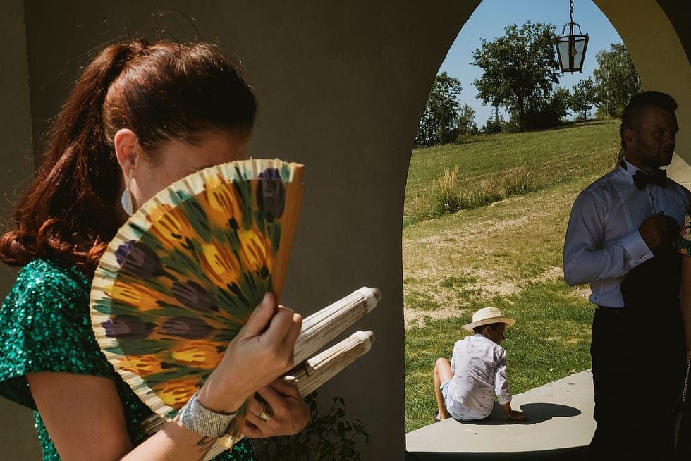 woman with fan, child framed in doorway and groosman preparing for wedding in Krakow