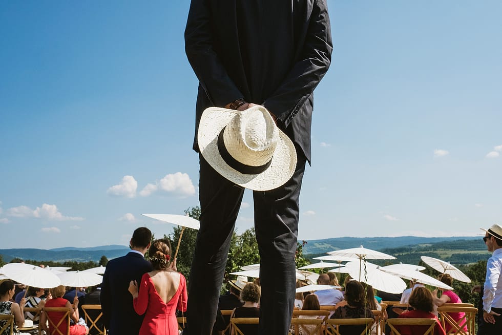 Man holding hat at back of outdoor wedding ceremony, Krakow